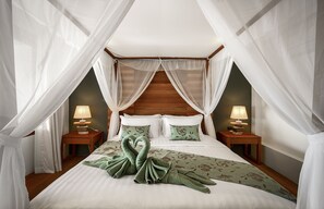 Une chambre à coucher avec un lit à baldaquin, deux lampes de chevet et une couvre-lit à motifs floraux.