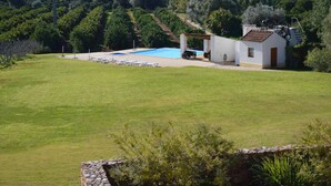 A pool area with a white building and a stone wall in the foreground. - 1-Bedroom apartment "Oliveira" – Pool view (2 + 2) (Mesquita)