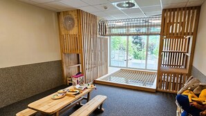 Ein Zimmer mit Holztisch, Bänken und einem Fenster mit Blick auf Grünflächen.
