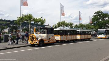 A tram with a clock face on the front, parked on a street with people around.