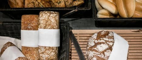 A variety of breads and pastries displayed in baskets and on a wooden surface.