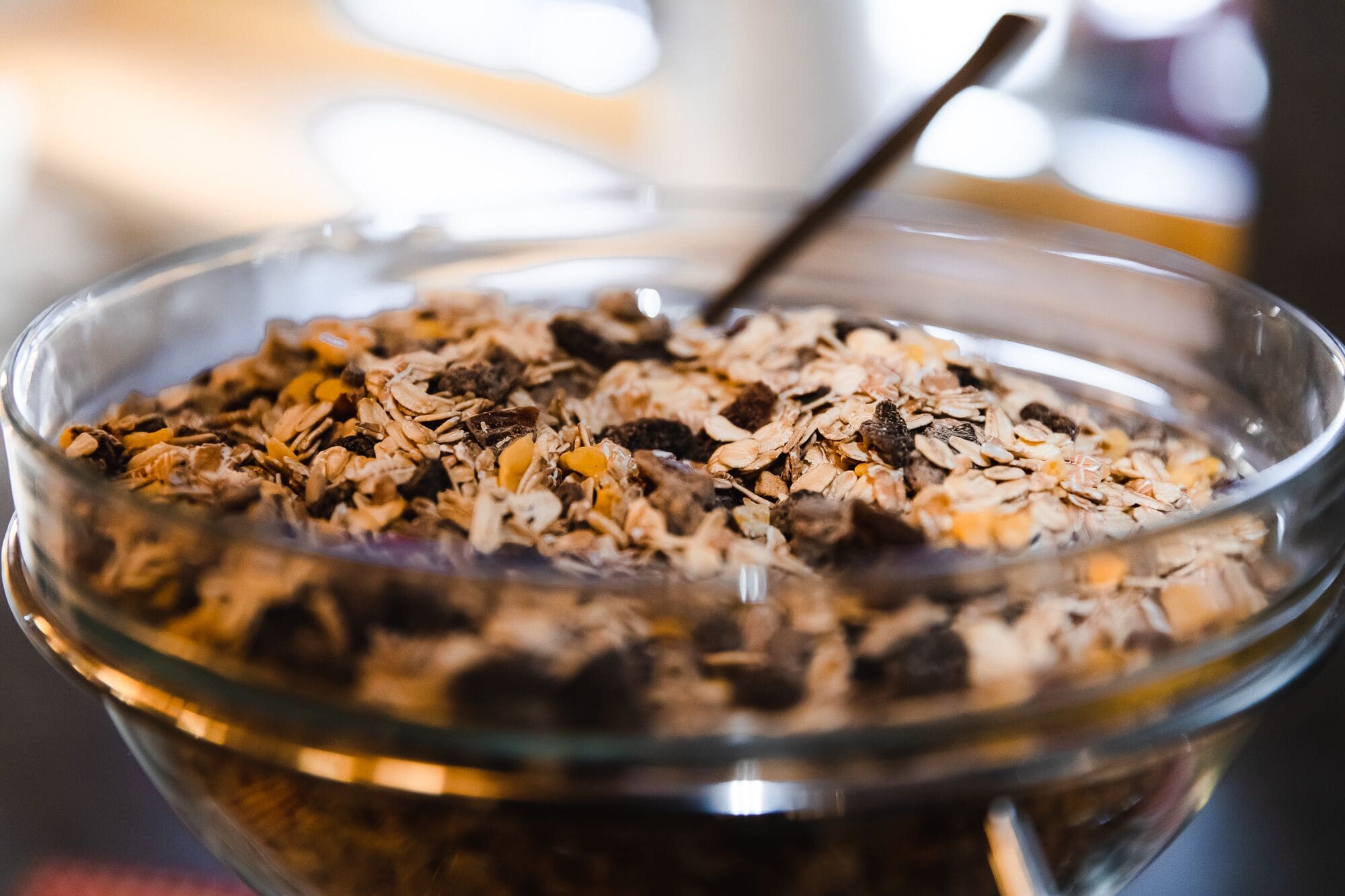 A glass bowl filled with a mix of oats and dried fruits.