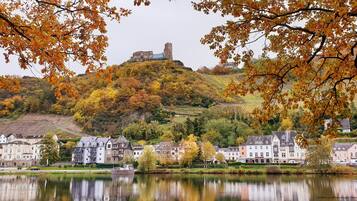 Eine historische Burg auf einem Hügel mit Blick auf eine Stadt mit traditionellen Gebäuden und einem ruhigen See.