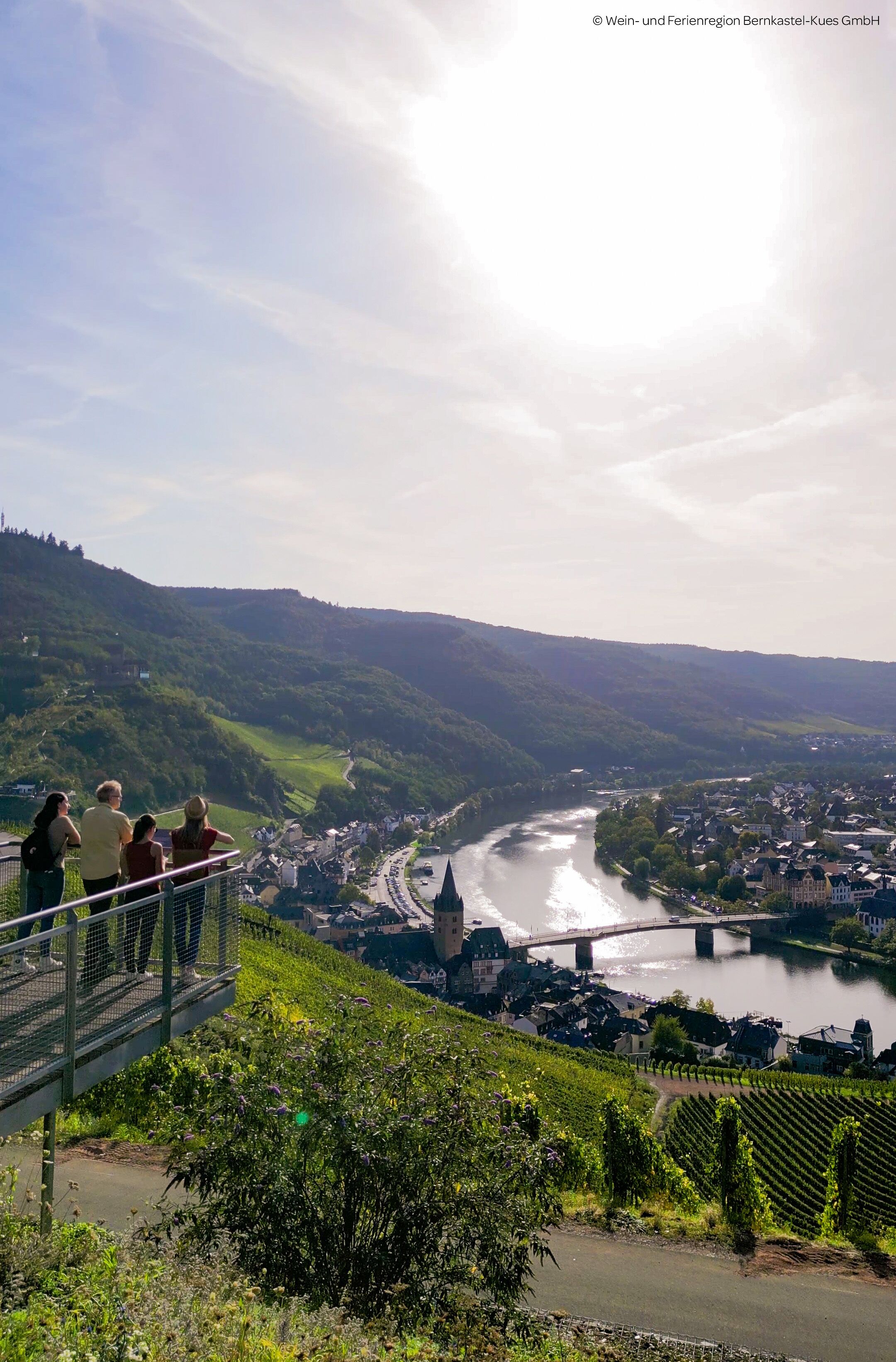 A scenic overlook with a river, bridge, and town below.