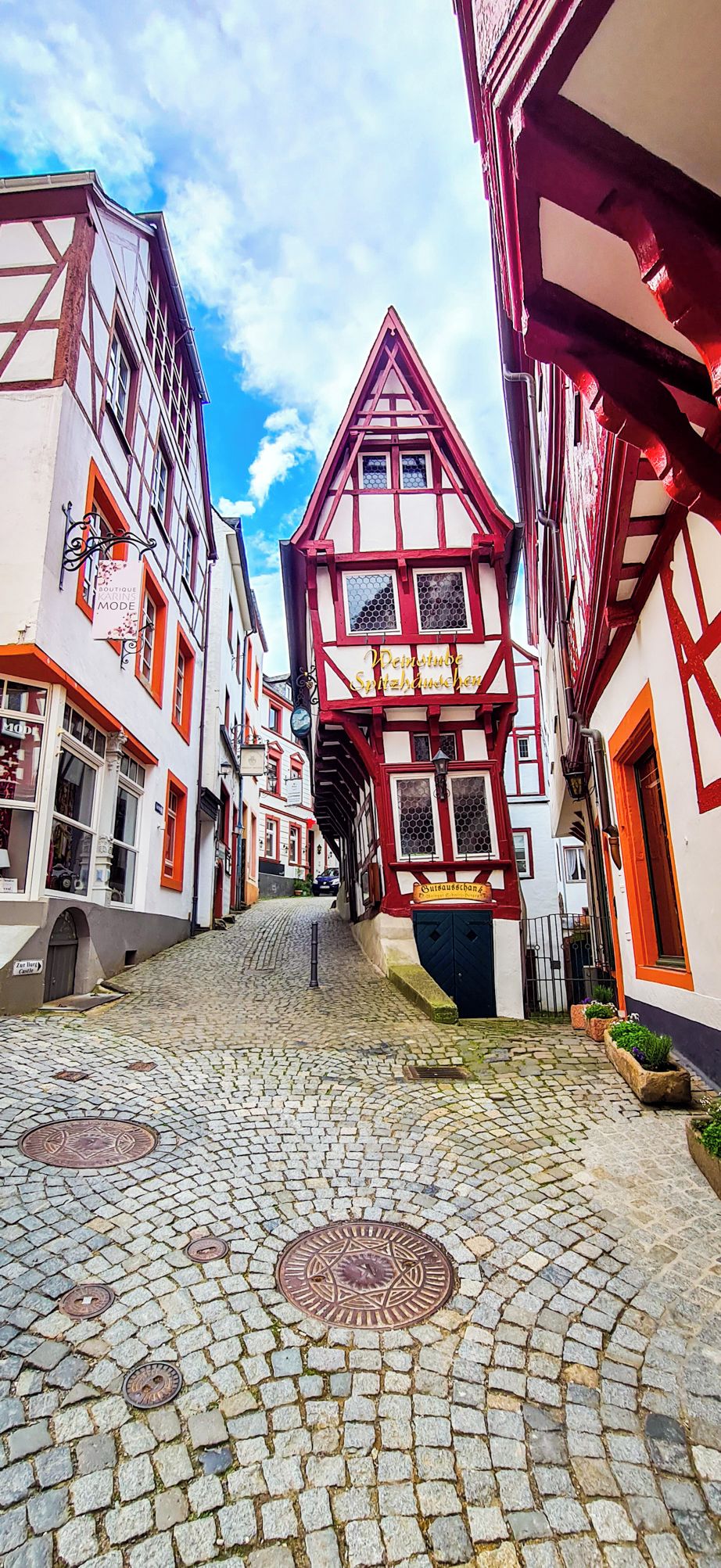 A cobblestone street lined with traditional half-timbered buildings, narrow passageway, and a clear sky.