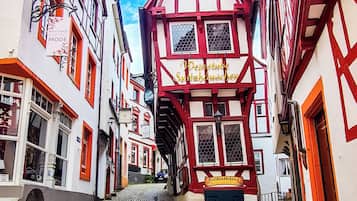 A cobblestone street lined with traditional half-timbered buildings, narrow passageway, and a clear sky.