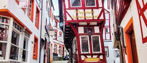 A cobblestone street lined with traditional half-timbered buildings, narrow passageway, and a clear sky.