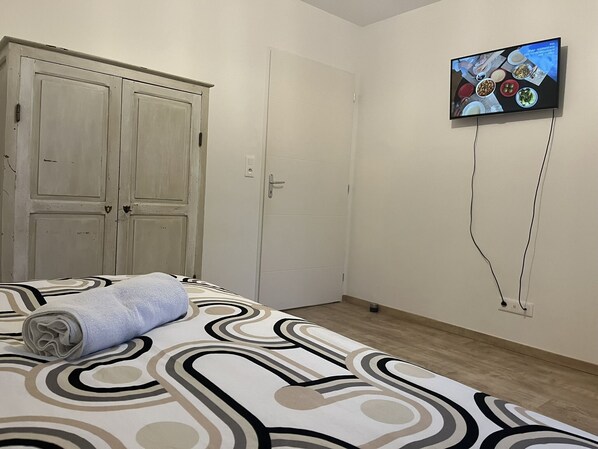Un dormitorio con una cama, un televisor montado en la pared y un armario.