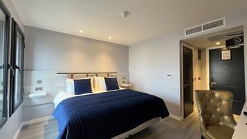 A modern bedroom with a bed, a chair, a bedside table, and a window.