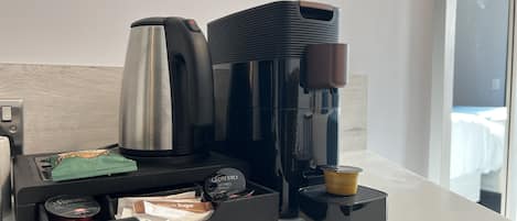 A coffee maker, a kettle, and a coffee pod holder with various coffee pods on a countertop.