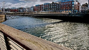A wooden bridge over a river with buildings in the background.