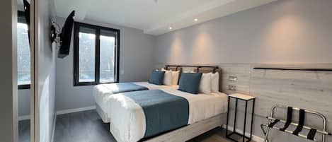 Un dormitorio moderno con una cama grande, una mesita de noche, una silla y una ventana.