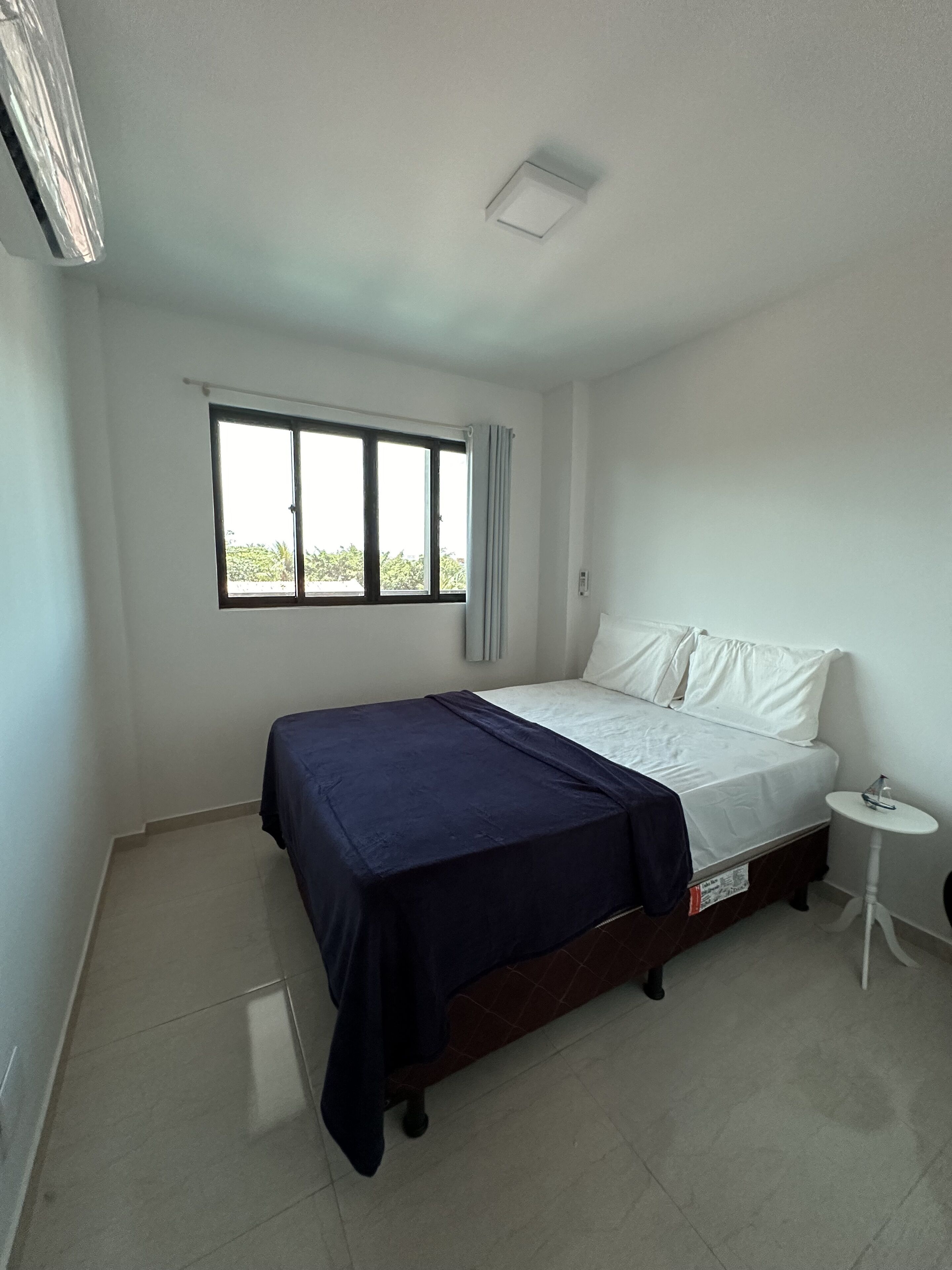Una camera da letto con un letto, una finestra, un tavolino e una lampada a soffitto.