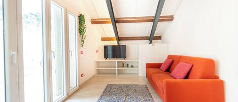 A modern living room with a sofa, TV, and a patterned rug.