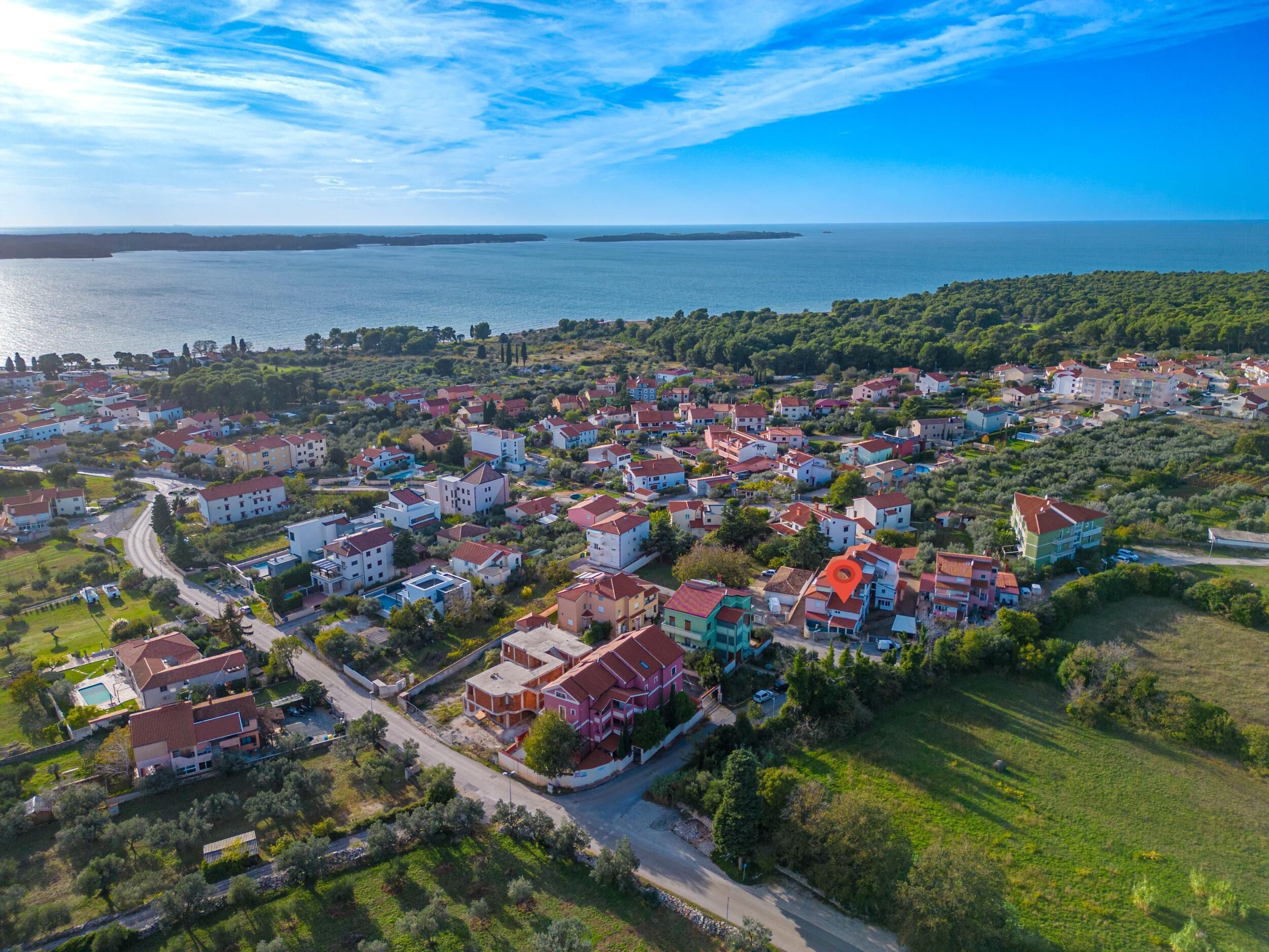 Una vista aerea di una zona residenziale costiera con case, strade e un corso d'acqua sullo sfondo.