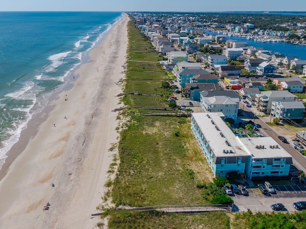 Vista aérea de una zona residencial costera con playa, casas y un puerto deportivo.