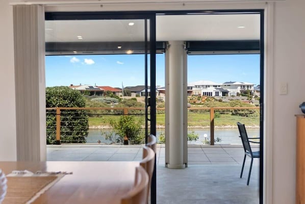 A room with a sliding glass door leading to a balcony with a view of a lake and houses. - 71 Blanche Pde Hindmarsh Island (Hindmarsh Island)