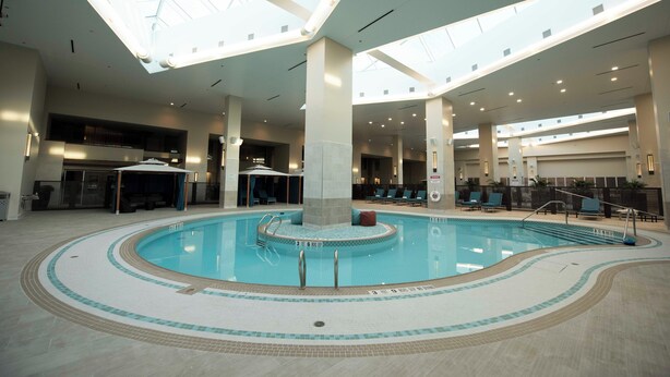 Una piscina interior con una columna central, suelo de baldosas y tragaluces.