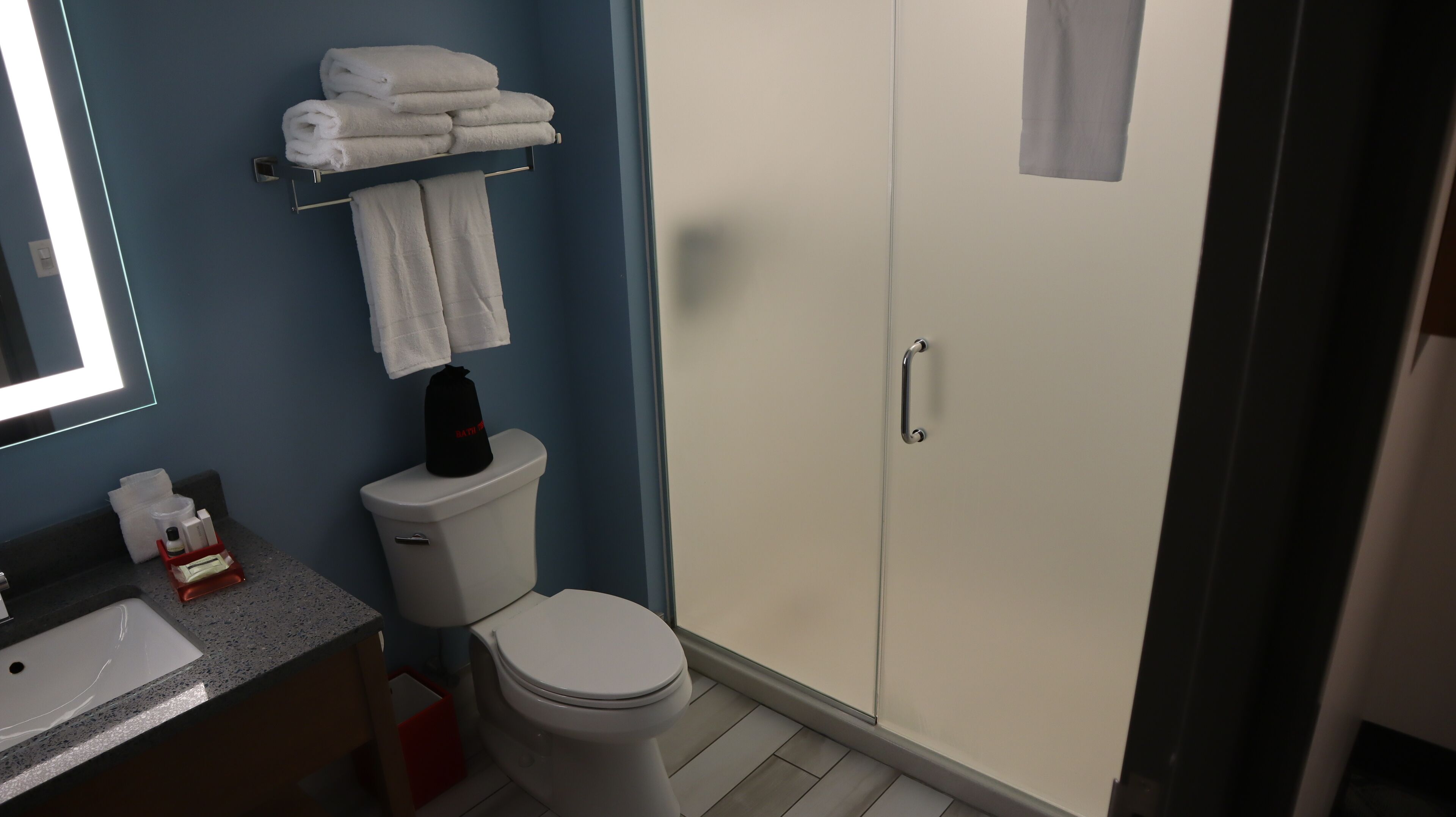 Ein Badezimmer mit Toilette, Waschbecken, Spiegel, Handtuchhalter mit Handtüchern und einem Schrank für Toilettenartikel.