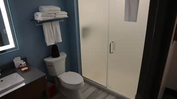 Un baño con inodoro, lavabo, espejo, toallero con toallas y un armario con artículos de aseo.