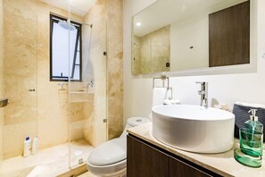 A modern bathroom with a glass-enclosed shower, a large sink, and a mirror above it.