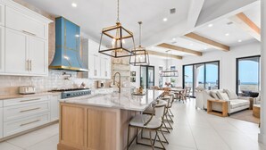 A modern kitchen with a large island, white cabinetry, and a blue accent wall.