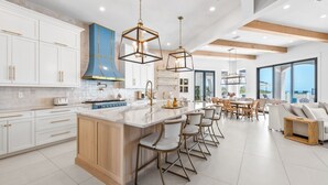 A modern kitchen with a central island, white cabinetry, and a blue accent wall.