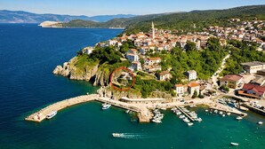 Vista aérea de un pueblo costero con un puerto deportivo, edificios y una iglesia destacada.