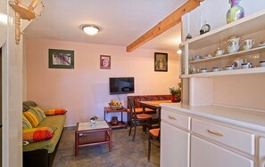 Una sala de estar acogedora con sofá, una mesa de centro, televisor y una zona comedor con sillas y mesa.