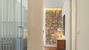 Ein Korridor mit einer Steinwand, Holzboden und einer Glastrennwand mit vertikalen Rollläden.