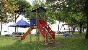 Ein Spielplatz mit Rutsche, Schaukeln und einer Kletterkonstruktion.