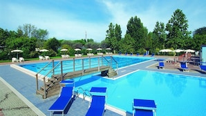 A large outdoor swimming pool with multiple lanes, surrounded by lounge chairs and umbrellas. - Ferienpark Cesenatico Mobilehome Riviera für 6 Personen (Cesenatico)