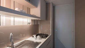 Eine moderne Küche mit Spüle aus Edelstahl, einem Gasherd und weißen Schränken.