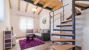 A modern living room with a wooden staircase, a grey sofa, and a purple rug. - Lovely apartment DESIREE in Rovinj (Rovinj)