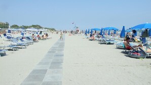 A beach with rows of blue umbrellas and lounge chairs.