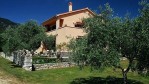 A two-story house with a stone wall and a garden in front.