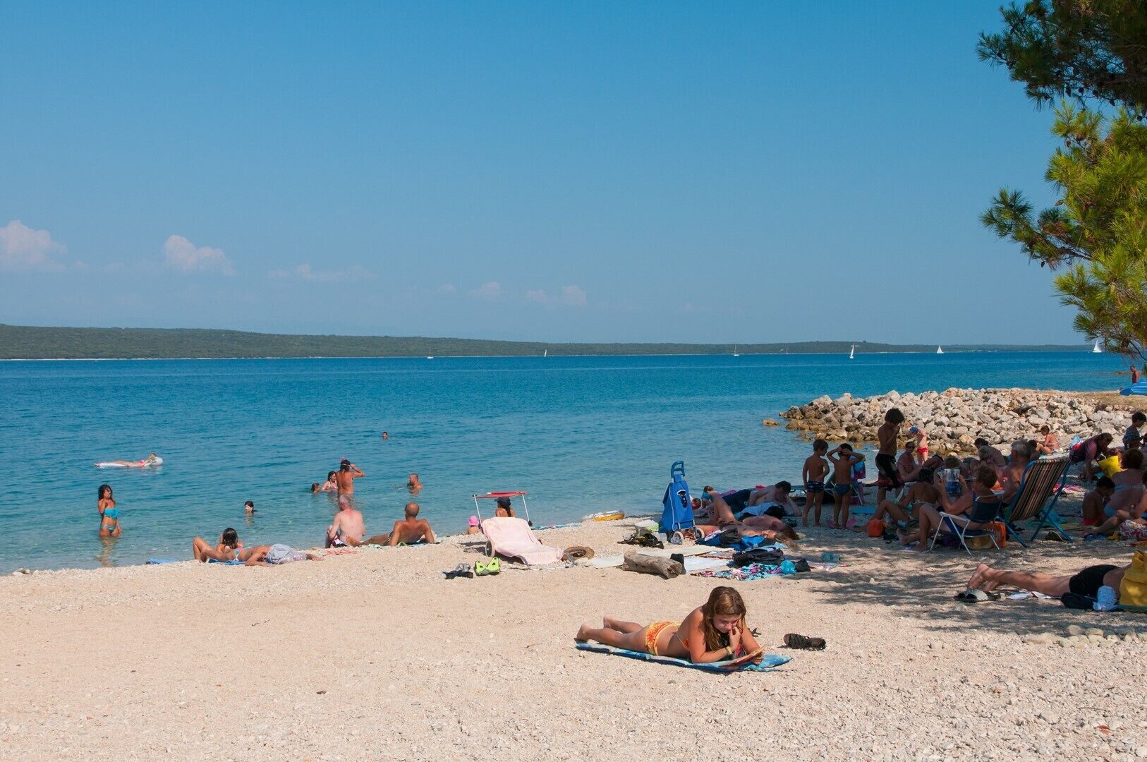 Une plage où des gens se prélassent au soleil et se baignent.