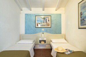 Cozy retreat with two single beds, a light blue accent wall, and a charming coastal scene painting.