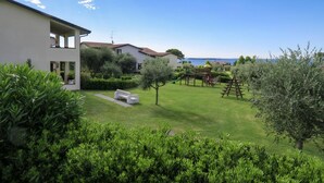 A residential property with a well-maintained lawn, a play area with a slide and climbing structure, and a view of the sea. - Residence Primera two-room apartment Tipo B2 for 4 persons (Moniga del Garda)