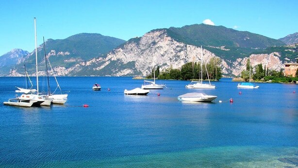 A clear view of a lake with boats, a sandy beach, and mountains in the background. - Residence Primera two-room apartment Tipo B2 for 4 persons (Moniga del Garda)