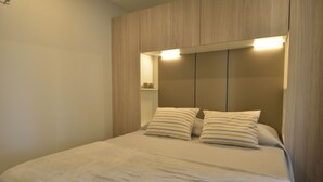 A bedroom with a bed, two pillows, and a headboard with built-in lighting.