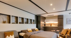 A modern hotel room with a large bed, a sofa, a small dining table, and a kitchenette. - Urban Flat 170 - Sublime Flat in Center of Paris (París)
