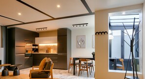 A modern kitchen with built-in appliances, a dining area with wooden furniture, and a large window providing natural light. - Urban Flat 170 - Sublime Flat in Center of Paris (París)