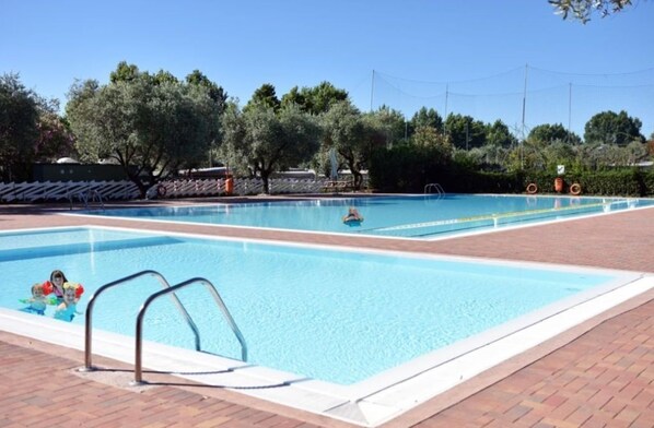 A rectangular swimming pool with a clear blue water surface, surrounded by a brick deck.