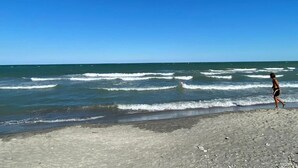 Een strand met golven en iemand die loopt.