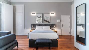 A modern bedroom with a large bed, bedside tables, a bench, and a large mirror.