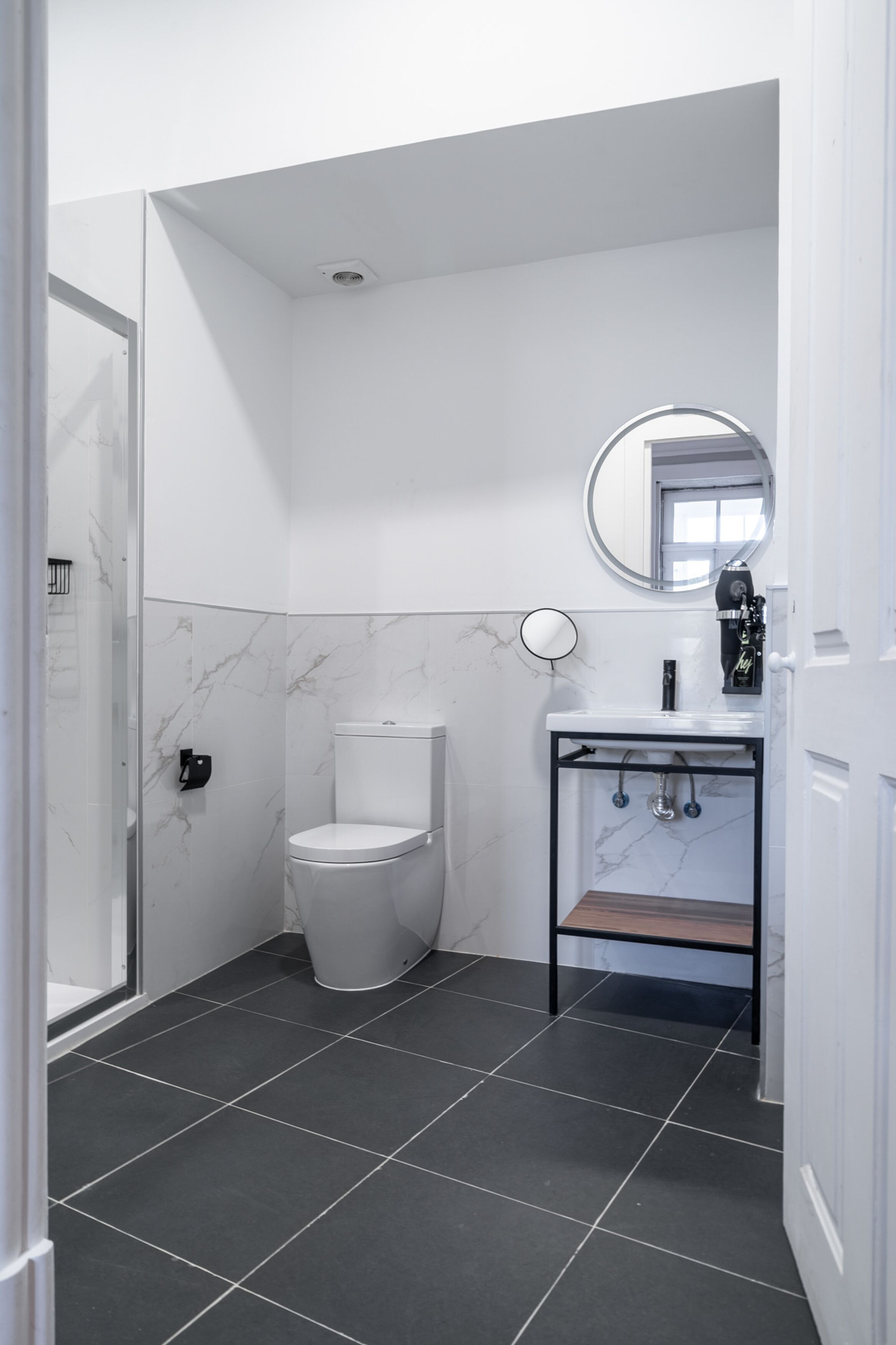 A modern bathroom with a toilet, a sink with a mirror, and a shower area.