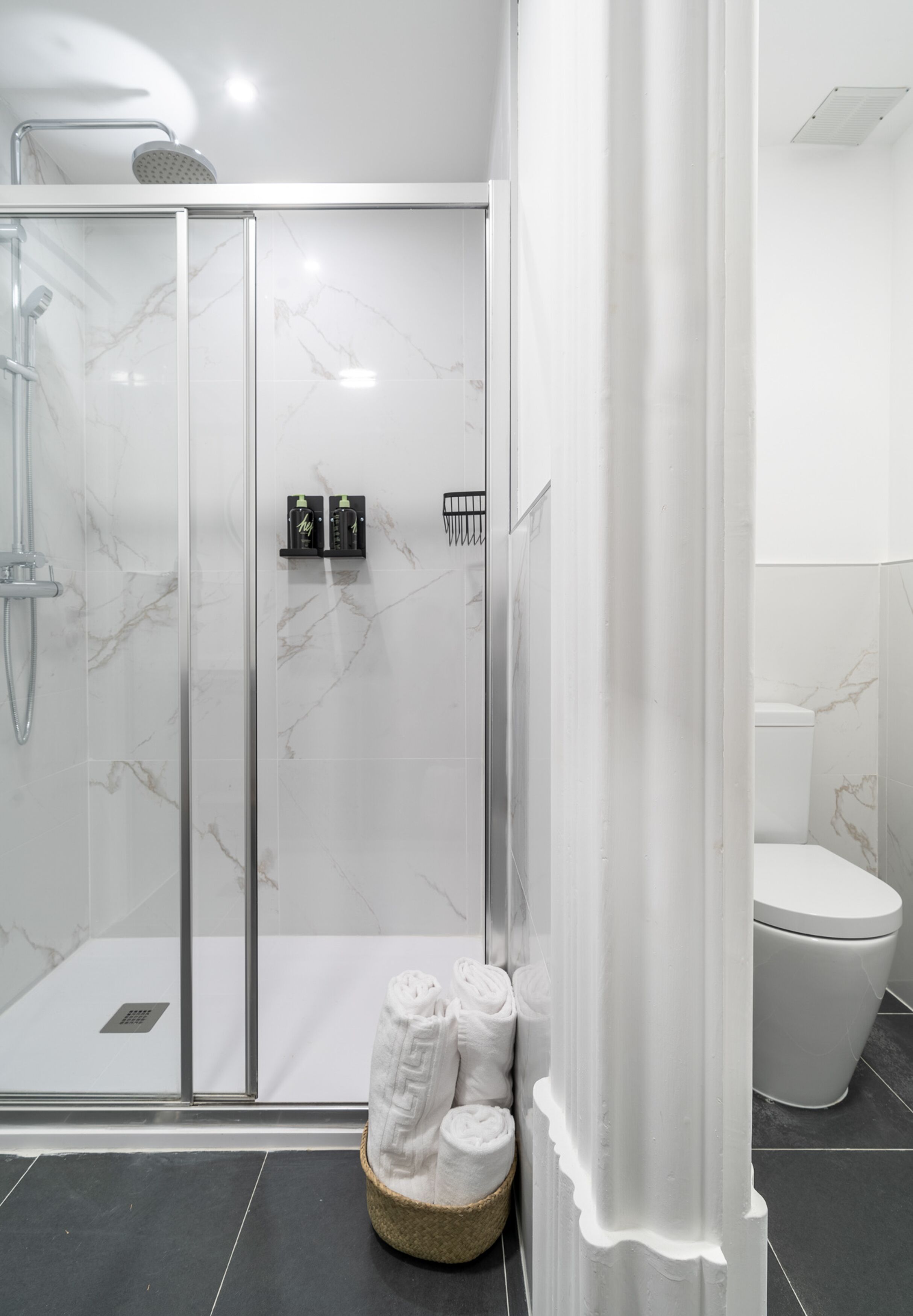 A modern bathroom with a glass-enclosed shower, a toilet, and a towel rack.