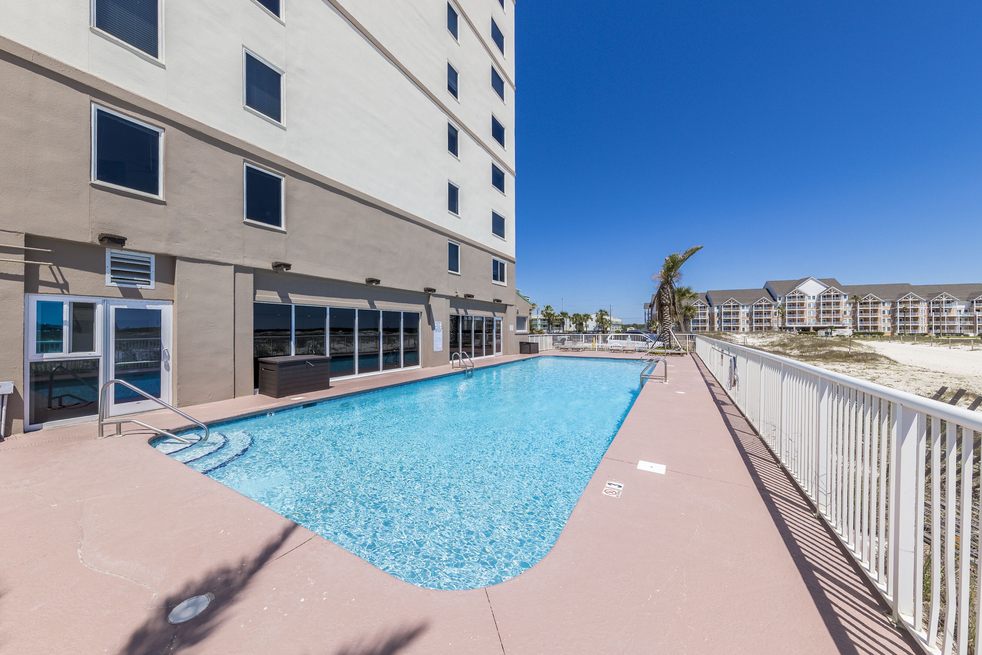 A swimming pool adjacent to a building with multiple windows and balconies.