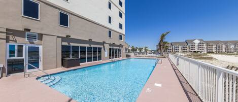 A swimming pool adjacent to a building with multiple windows and balconies.